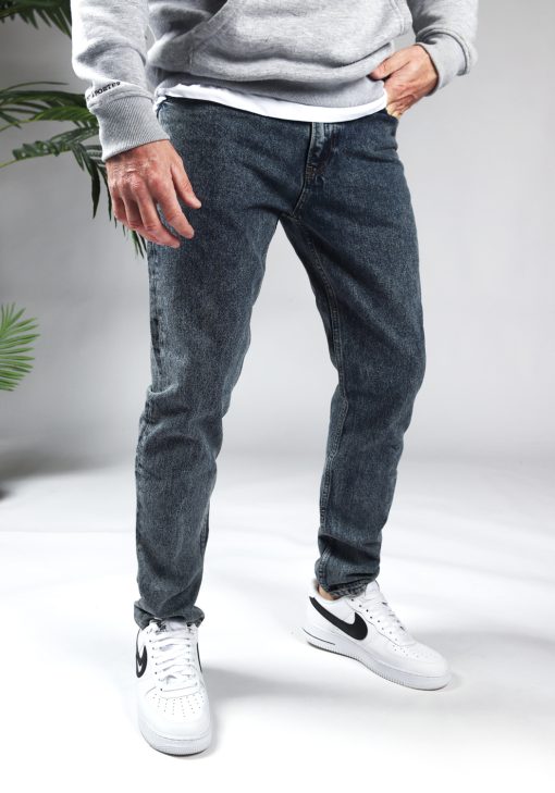 Voorkant denim heren jeans met loose fit, gecombineerd met grijze hoodie en witte sneakers