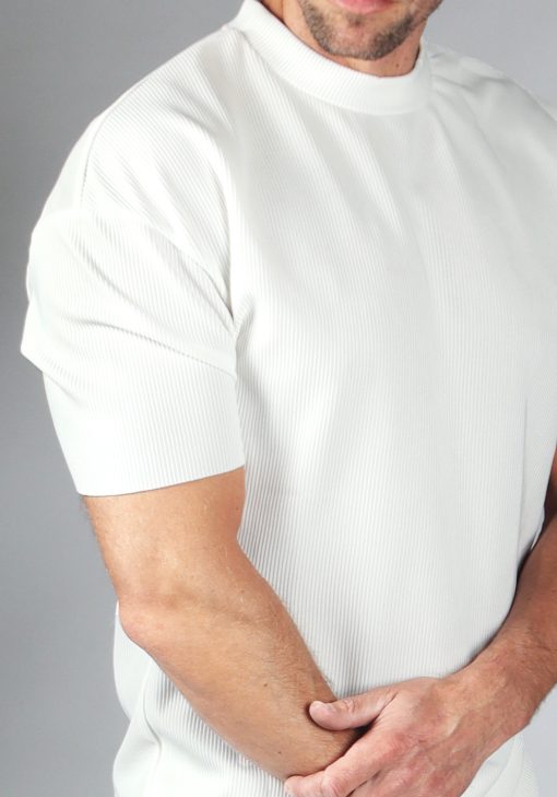 Close up van model gekleed in witte rib top met korte mouwen. Het model heeft een hand over zijn arm.