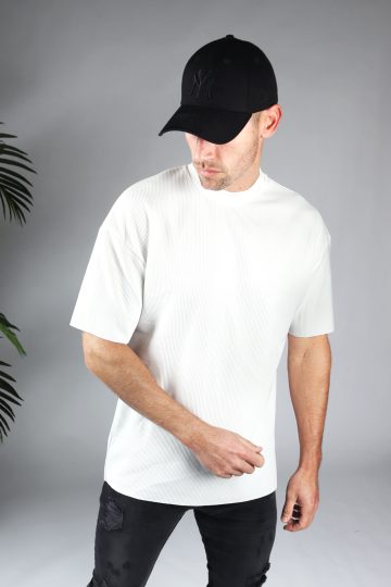 Vooraanzicht van geribd heren T-shirt in witte kleur en ronde hals. Het model draagt een donkere jeans en een zwarte pet.