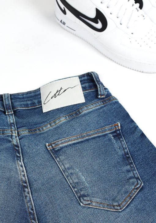 Close up Cotton-logo op acherzijde denim heren jeans met damaged look en verfspetters.