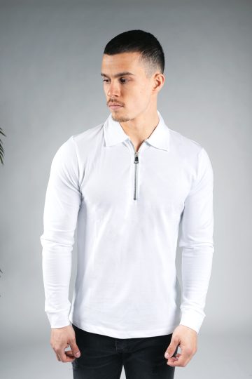 Vooraanzicht van model gekleed in een witte longsleeve polo trui met halve rits. Het model heeft zijn armen naast zijn lichaam en kijkt schuin naar rechts.