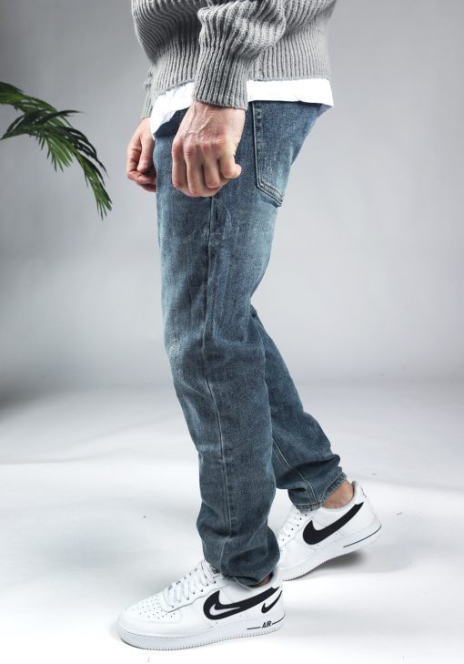 Zijaanzicht blauwe denim heren jeans met loose fit en damaged uitstraling
