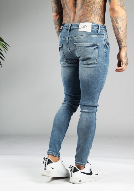 Achterzijde blauwe denim heren jeans skinny pasvorm van stretch stof. Voorzien van zakken aan de voor- en achterzijde, knoopsluiting en riemlussen.