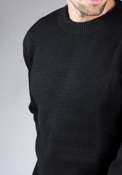 Close up van model gekleed in een zwarte knit sweater met een oversized fit.