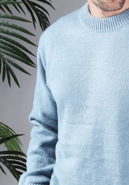 Close up van model gekleed in een lichtblauwe knit sweater met een oversized fit.