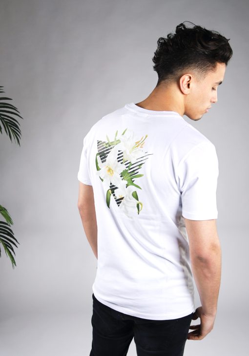 Achteraanzicht van model gekleed in wit t-shirt met driekhoek bloemenprint op de rug, en het kleine zwarte logo op de borst.