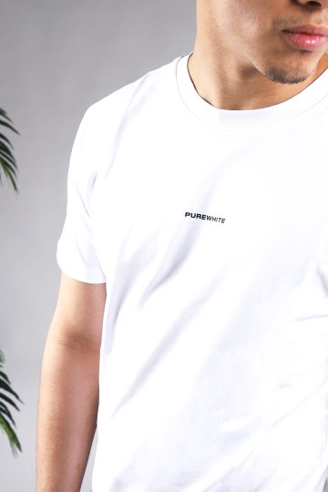 Close up vooraanzicht van model gekleed in wit t-shirt met driekhoek bloemenprint op de rug, en het kleine zwarte logo op de borst.