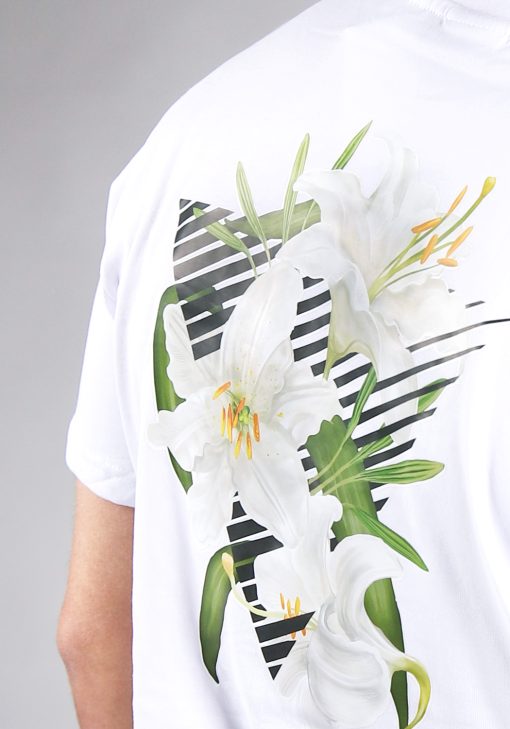 Close up achteraanzicht van model gekleed in wit t-shirt met driekhoek bloemenprint op de rug, en het kleine zwarte logo op de borst.