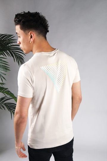 Achteraanzicht van model gekleed in zandkleurig t-shirt met gestreepte driehoek print op de rug en het kleine logo op de borst. De prints hebben een faded kleur van mintgroen, naar wit, tot geel.