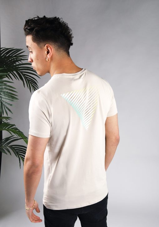 Achteraanzicht van model gekleed in zandkleurig t-shirt met gestreepte driehoek print op de rug en het kleine logo op de borst. De prints hebben een faded kleur van mintgroen, naar wit, tot geel.