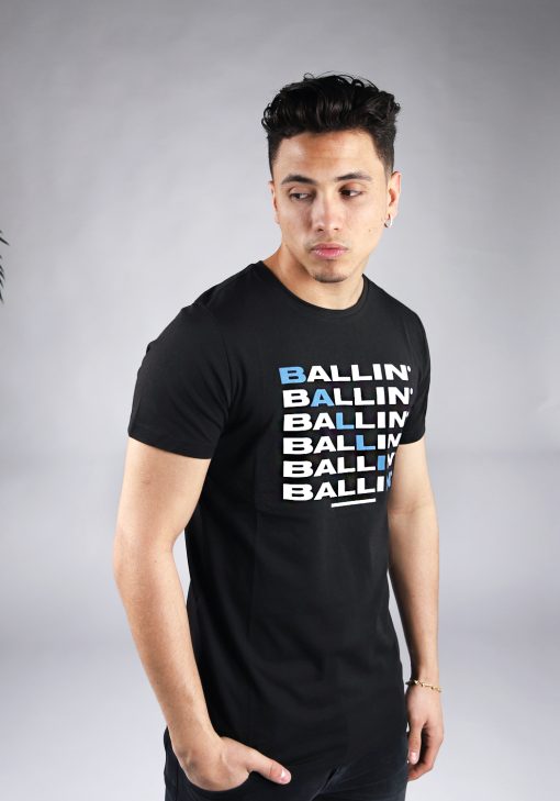 Schuin vooraanzicht van model gekleed in zwart t-shirt met zes keer de witte tekst Ballin op de voorkant. Diagonaal zijn de letters een voor een blauw en maken ook zo het woord Ballin.