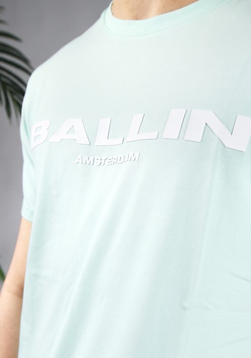 Close up vooraanzicht van model gekleed in mintgroen t-shirt met de witte tekst Ballin Amsterdam op de voorkant.
