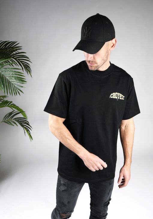 Schuin vooraanzicht van heren T-shirt in zwarte kleur, met een ronde hals en een box fit pasvorm. Het T-shirt is voorzien van tekst op de linkerborst.