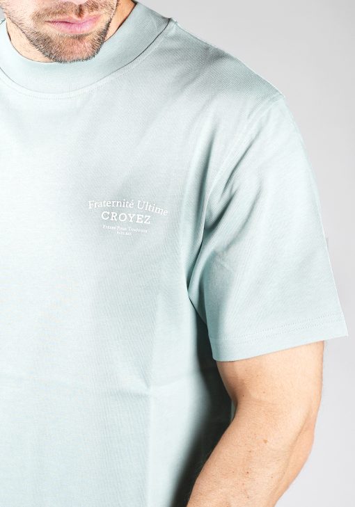 Close-up van heren T-shirt in blauwe kleur, met een ronde hals en een box fit pasvorm. Het T-shirt is voorzien van witte tekst op de achterkant.