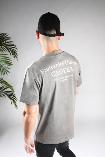 Schuin achteraanzicht van heren T-shirt in grijze kleur, met een ronde hals en een box fit pasvorm. Het T-shirt is voorzien van witte tekst op de achterkant.