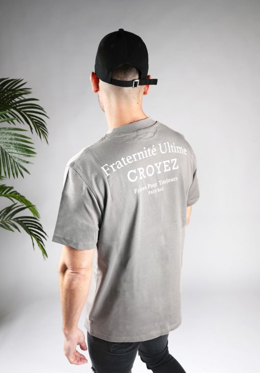 Schuin achteraanzicht van heren T-shirt in grijze kleur, met een ronde hals en een box fit pasvorm. Het T-shirt is voorzien van witte tekst op de achterkant.