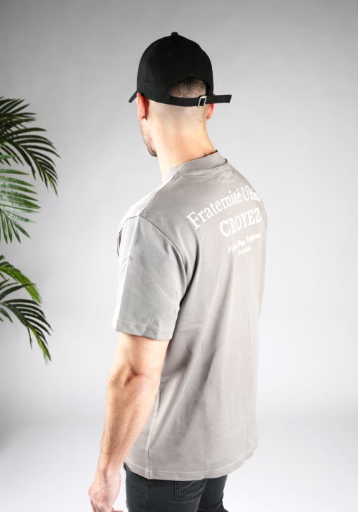 Achter zijaanzicht van heren T-shirt in grijze kleur, met een ronde hals en een box fit pasvorm. Het T-shirt is voorzien van witte tekst op de achterkant.