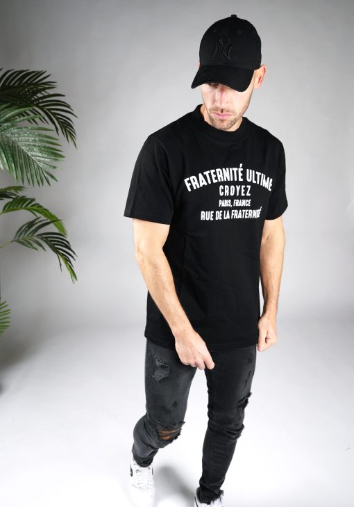 Schuin vooraanzicht van heren T-shirt in zwarte kleur, met een ronde hals en een box fit pasvorm. Het T-shirt is voorzien van witte tekst op de voorkant.