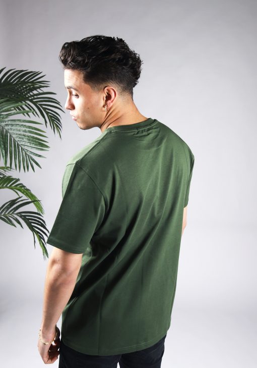 Schuin achteraanzicht van model gekleed heren T-shirt in groene kleur, met ronde hals en een relaxed fit pasvorm.
