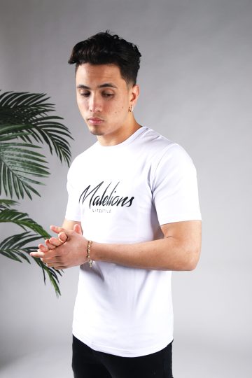 Schuin vooraanzicht van model gekleed in wit Malelions t-shirt met een zwart logo en zwarte tekst op de voorkant.