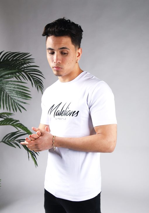 Schuin vooraanzicht van model gekleed in wit Malelions t-shirt met een zwart logo en zwarte tekst op de voorkant.