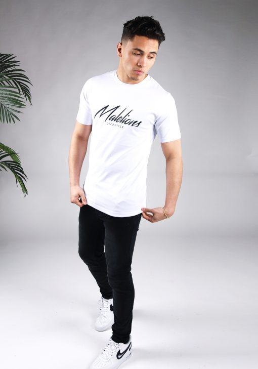 Full body vooraanzicht van model gekleed in wit Malelions t-shirt met een zwart logo en zwarte tekst op de voorkant.