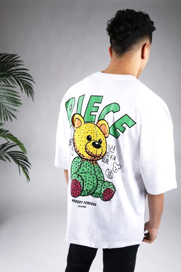 Achteraanzicht van een heren T-shirt in witte kleur en een super oversized pasvorm. Het T-shirt is voorzien van groene tekst en een beer op de achterkant. Het model laat zijn armen langs zijn lichaam hangen en draagt een donkere jeans.