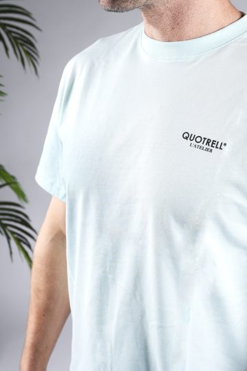 Close up van linker vooraanzicht van een heren T-shirt in blauwe kleur met een ronde hals en een relaxed fit pasvorm. Het T-shirt is voorzien van het QUOTRELL logo op de linkerborst.