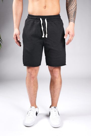 Vooraanzicht van model gekleed in zwarte jogger shorts met witte touwtjes. Het model heeft zijn armen naast zich en draagt witte sneakers.