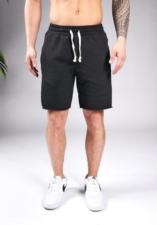Vooraanzicht van model gekleed in zwarte jogger shorts met witte touwtjes. Het model heeft zijn armen naast zich en draagt witte sneakers.