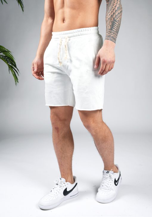 Linker vooraanzicht van model gekleed in witte jogger shorts met witte touwtjes. Het model heeft zijn handen naast zich en draagt witte sneakers.