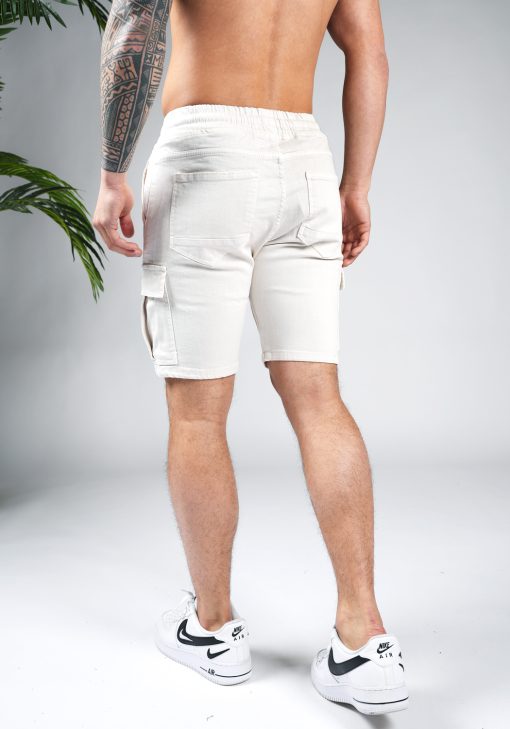 Achteraanzicht van model gekleed in zandkleurige cargo shorts in combinatie met witte sneakers.