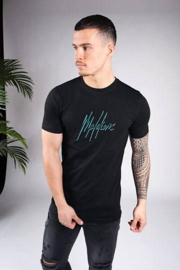 Vooraanzicht van model gekleed in zwart Malelions t-shirt met het dubbel geborduurde logo in de kleuren turquoise en zwart op de borst. Het model heeft zijn armen losjes langs zich en kijkt naar rechts.