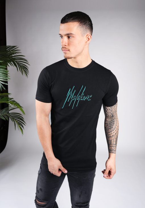 Vooraanzicht van model gekleed in zwart Malelions t-shirt met het dubbel geborduurde logo in de kleuren turquoise en zwart op de borst. Het model heeft zijn armen losjes langs zich en kijkt naar rechts.