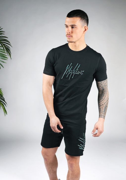 Vooraanzicht van model gekleed in zwarte Malelions set. De set bestaat uit een zwart t-shirt met het zwart-turquoise Malelions logo op de borst, en de jogger shorts met het grote logo verticaal op de been.