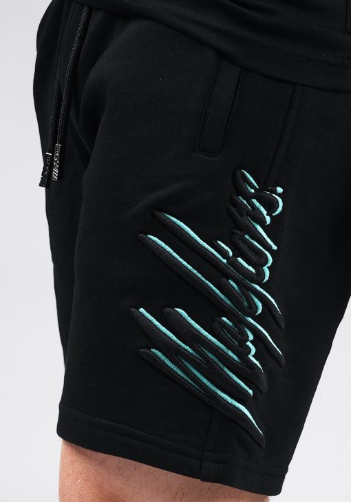 Close up broek van model gekleed in zwarte Malelions set. De set bestaat uit een zwart t-shirt met het zwart-turquoise Malelions logo op de borst, en de jogger shorts met het grote logo verticaal op de been.