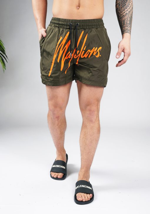 Vooraanzicht van model gekleed in legergroene swimshorts met het grote oranje Malelions logo op de voorkant.