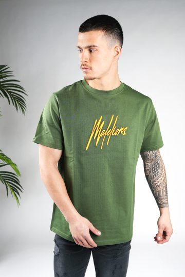 Vooraanzicht van model gekleed in een heren T-shirt in groene kleur, met een ronde hals en een relaxed fit pasvorm. Het T-shirt is voorzien van het Malelions-logo in het oranje op de borst.