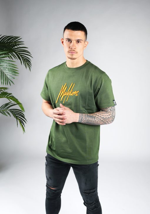 Linker vooraanzicht van model gekleed in een heren T-shirt in groene kleur, met een ronde hals en een relaxed fit pasvorm. Het T-shirt is voorzien van het Malelions-logo in het oranje op de borst.
