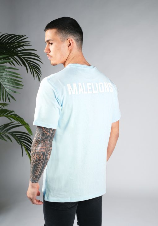 Schuin achteraanzicht van model gekleed in een lichtblauw gekleurd heren T-shirt. Het T-shirt is voorzien van het MALELIONS-logo op de borst in witte kleur op de achterkant.
