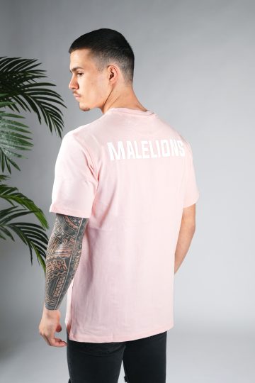 Schuin achteraanzicht van model gekleed in een lichtroze gekleurd heren T-shirt. Het T-shirt is voorzien van het MALELIONS-logo op de borst in witte kleur op de achterkant.