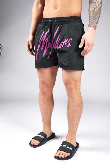 Vooraanzicht van model gekleed in zwarte swimshorts met het grote paarse Malelions logo op de voorkant.