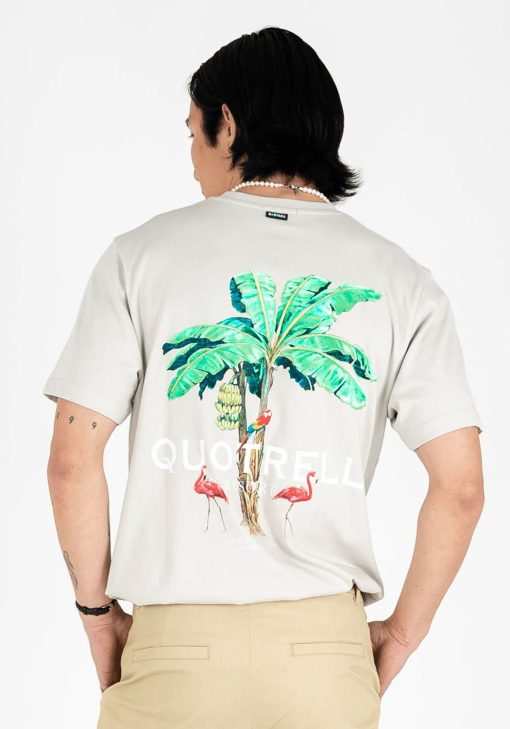 Achteraanzicht van model gekleed in een heren T-shirt in lichtgrijze kleur, met een ronde hals en een relaxed fit pasvorm. Het T-shirt is voorzien van palmboom print, flamingo's en lichte tekst op de achterkant.