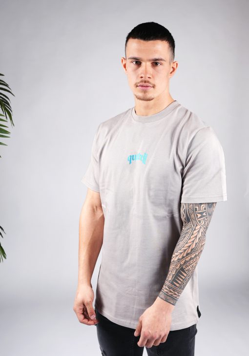Vooraanzicht van model gekleed in een T-shirt in taupe kleur en met een relaxed fit pasvorm. Het T-shirt is voorzien van tekst in blauwe kleur op de borst.