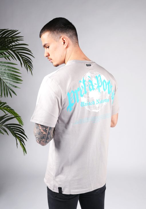 Schuin achteraanzicht van model gekleed in een T-shirt in taupe kleur en met een relaxed fit pasvorm. Het T-shirt is voorzien van tekst in blauwe kleur en een witte wereldbol.