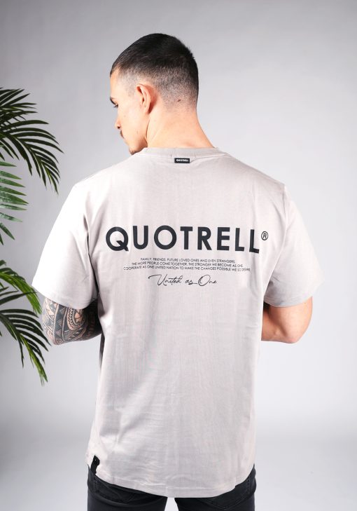 Achteraanzicht van model gekleed in een heren T-shirt in taupe kleur en met ronde hals. Het T-shirt is voorzien van het QUOTRELL-logo en zwarte tekst op de rug.