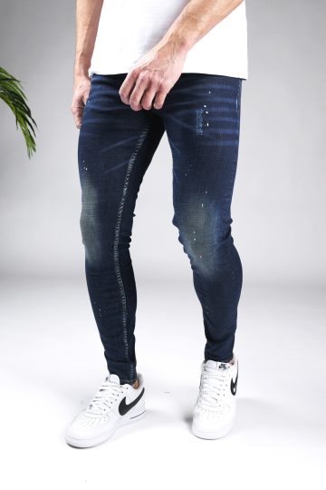 Linker zijaanzicht donkerblauwe heren skinny jeans met verfspetters en damaged afwerken, gemaakt van stretch stof. Voorzien van vier zakken, knoopsluiting en riemlussen.