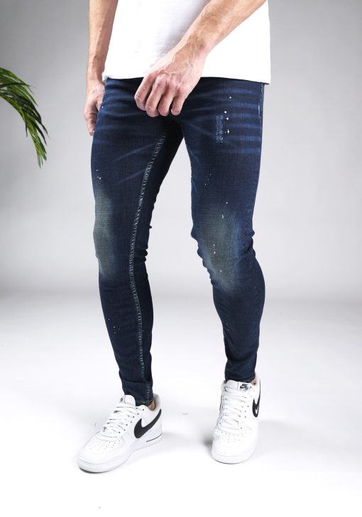 Linker zijaanzicht donkerblauwe heren skinny jeans met verfspetters en damaged afwerken, gemaakt van stretch stof. Voorzien van vier zakken, knoopsluiting en riemlussen.